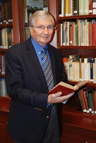 A person in a suit holding a book

Description automatically generated